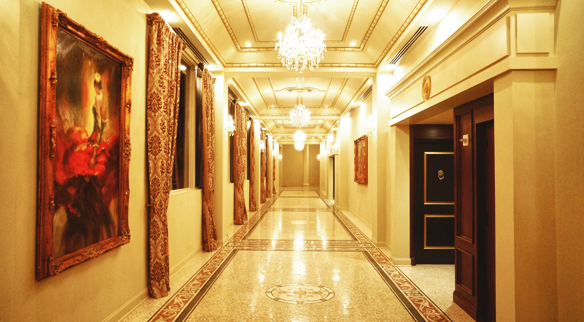 Chandelier-lit hallway with marble floors and framed artwork